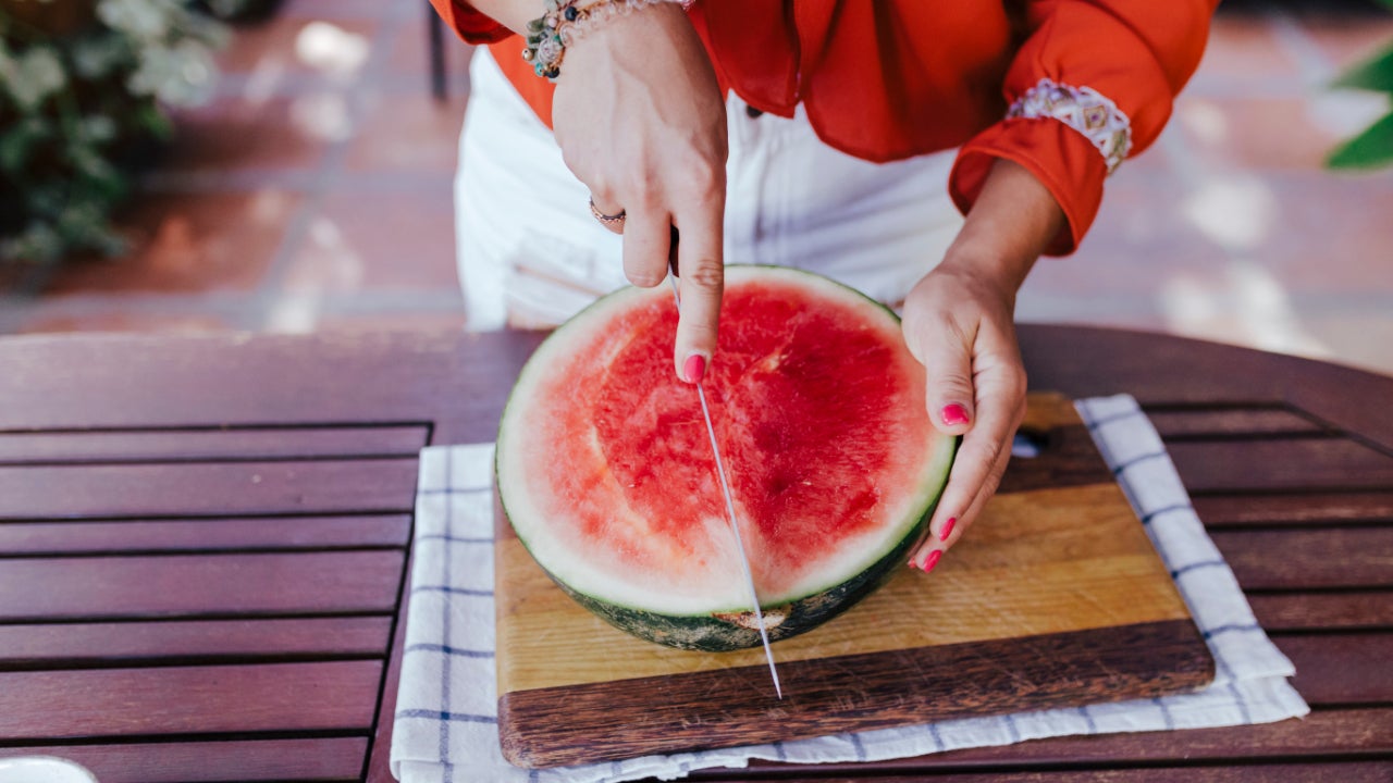 Person cutting a watermelon in half.