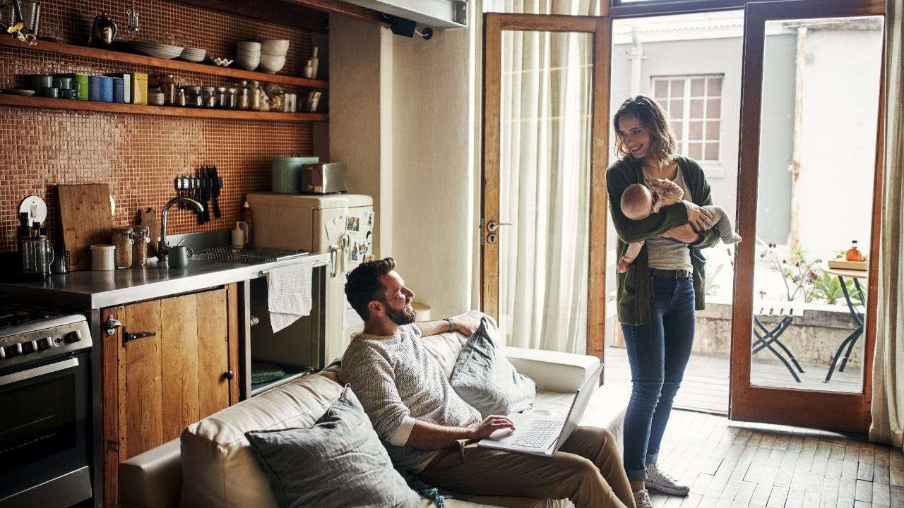 Person holding baby looking at person sitting on couch