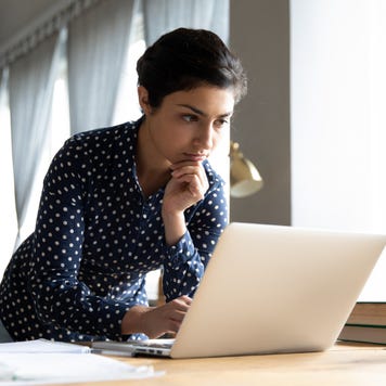 A young Indian woman looks over a laptop