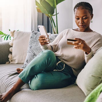 woman sitting on couch looking at credit card