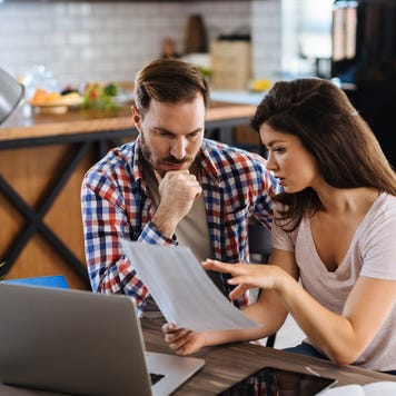 Frustrated couple checking bills at home using laptop