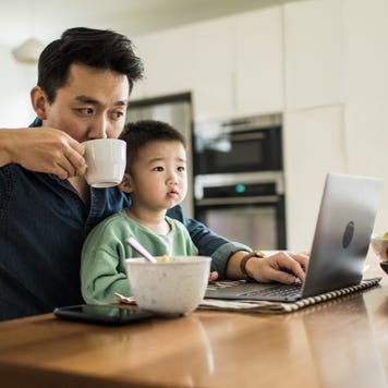 A father multi-tasks with his young son.