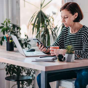 Woman working on laptop and smartphone
