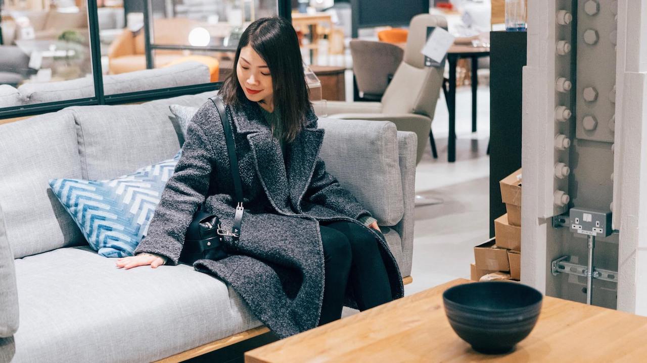 Young woman at furniture store choosing sofa