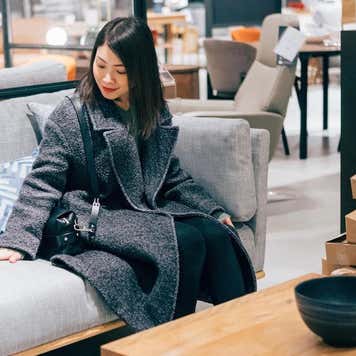 Young woman at furniture store choosing sofa