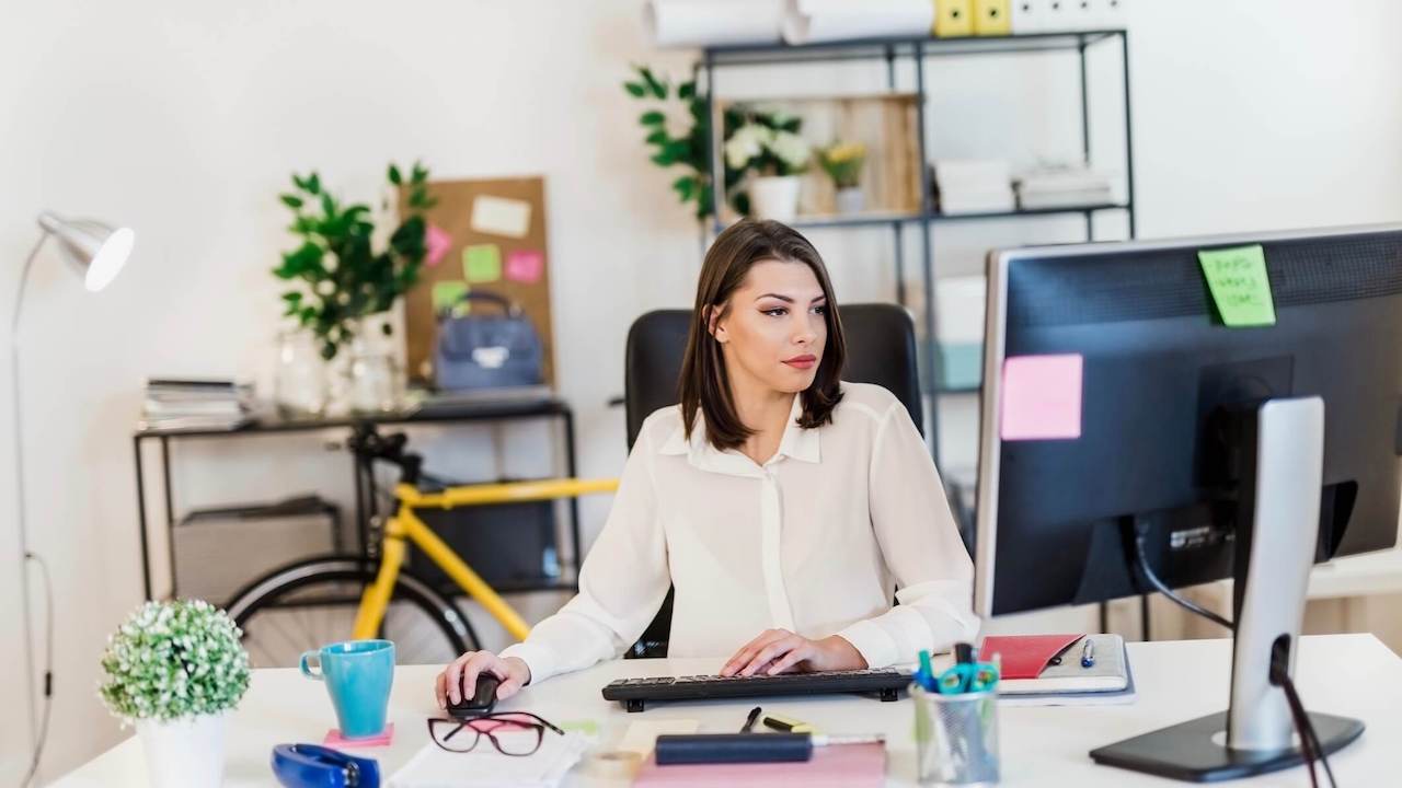 Young woman working in her office, typing on a desktop PC keyboard