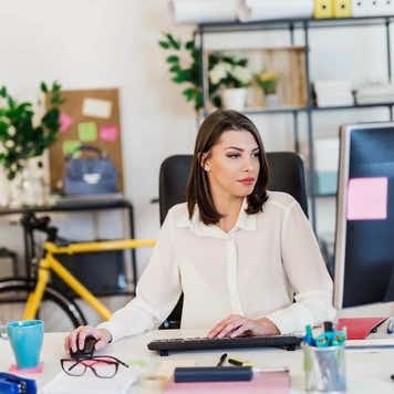 Young woman working in her office, typing on a desktop PC keyboard