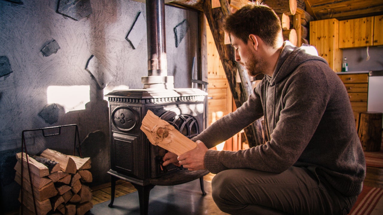 Young Man Putting Firewood in Wood Burning Stove
