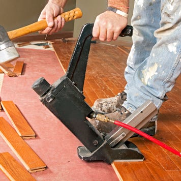 A carpenter lays hardwood flooring