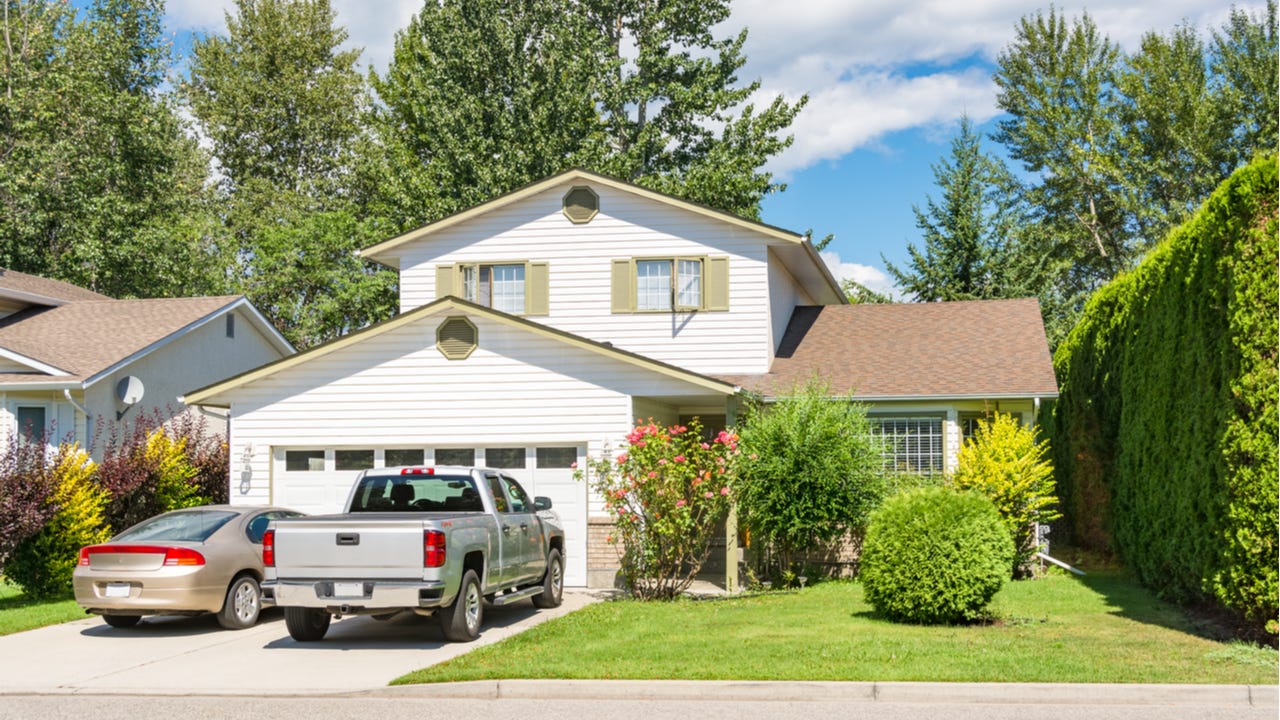 A single-family home with attached garage and two cars in the driveway