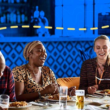 Friends laugh while gathered at a table eating a meal and socialization.
