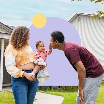 BIPOC couple holding a child from front of a house