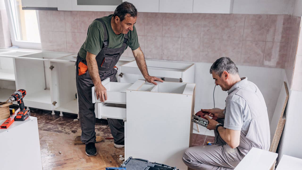 two men working on a cabinet during kitchen renovation