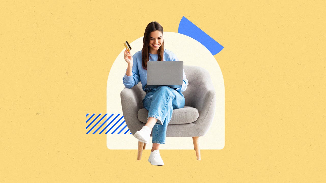 Woman seated on a chair, smiling with a laptop on her lap, holding a credit card