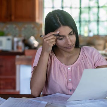 Young concerned woman looks at her bills at the kitchen table