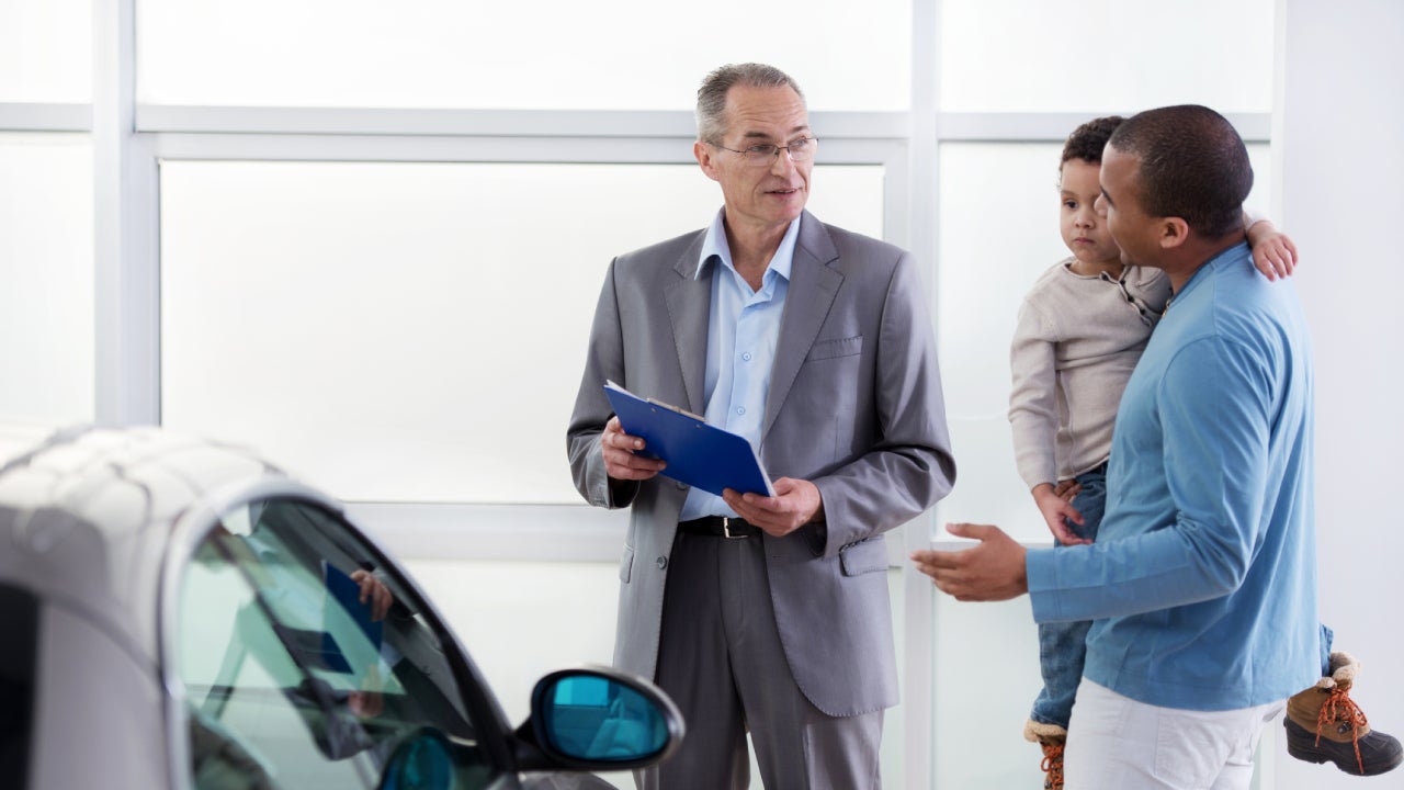 African American father and son discussing with a car salesperson.