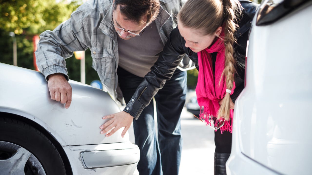 Man and woman looking car after accident.