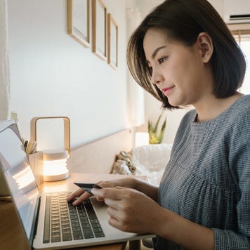 Young woman using a laptop with credit card while relaxing at home