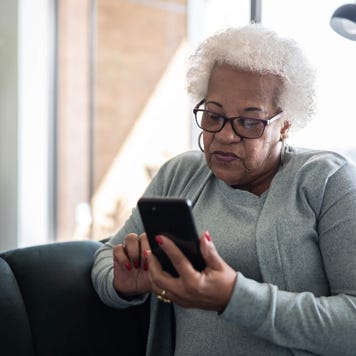 Senior woman using smartphone sitting on the couch at home