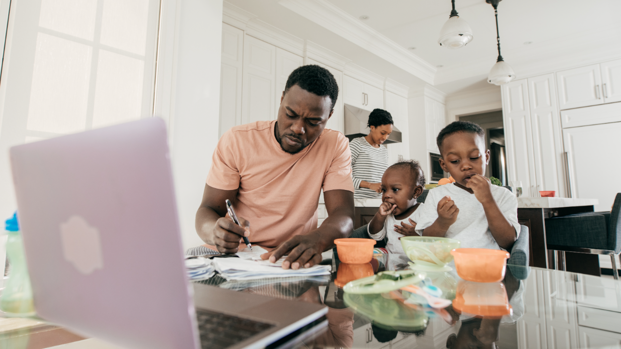 Father works on a computer next to children.