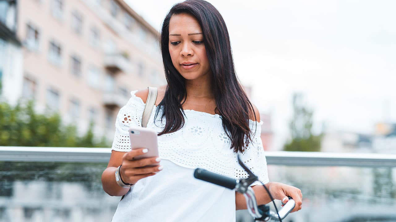 person standing next to bike and looking at phone