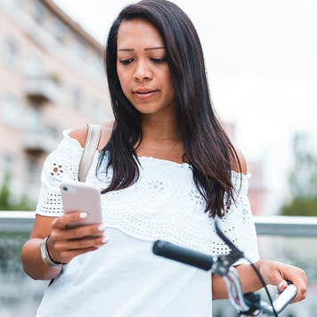 person standing next to bike and looking at phone
