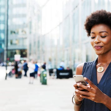 Woman using mobile next to buildings