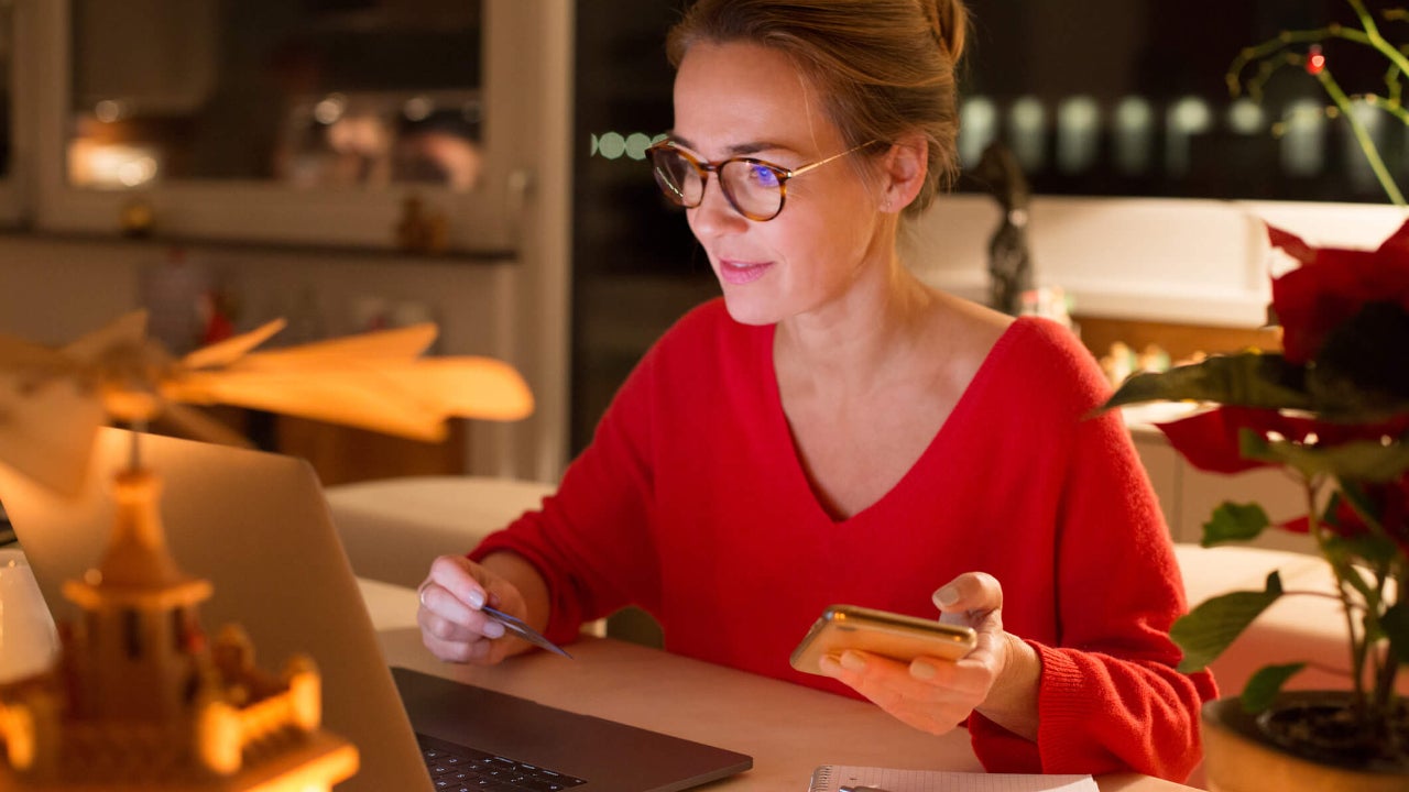 Woman using credit card for online shopping in her kitchen during winter holidays