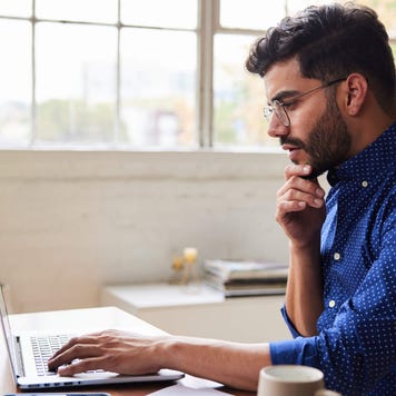 Young man using a laptop with a deep-in-thought expression