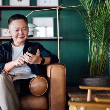 Senior man using smartphone while relaxing on the sofa in the living room at home