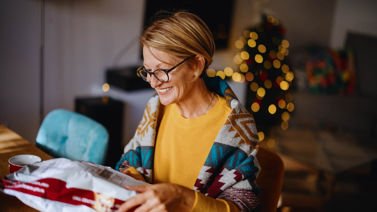 Smiling woman unpacking parcel sitting at home