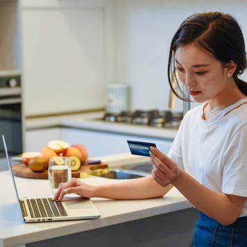 Young woman using a credit card at home to online shop
