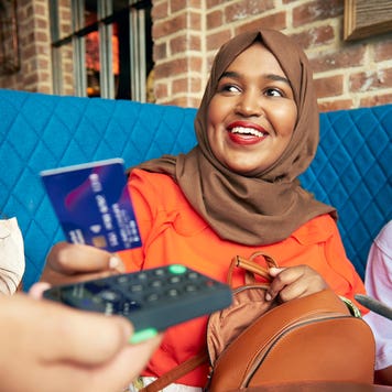 women wearing hijab hands over her credit card to pay at a restaurant