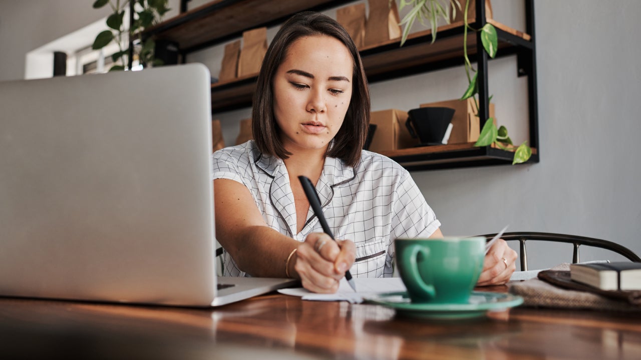 Shot of a young woman using a laptop in a cafe