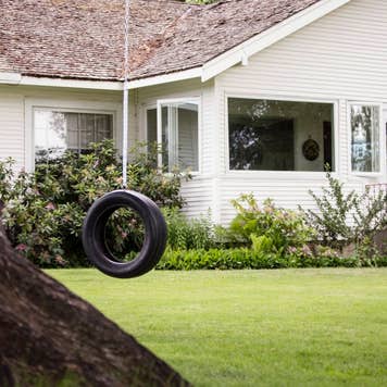 Tire swing hanging on a tree at a house