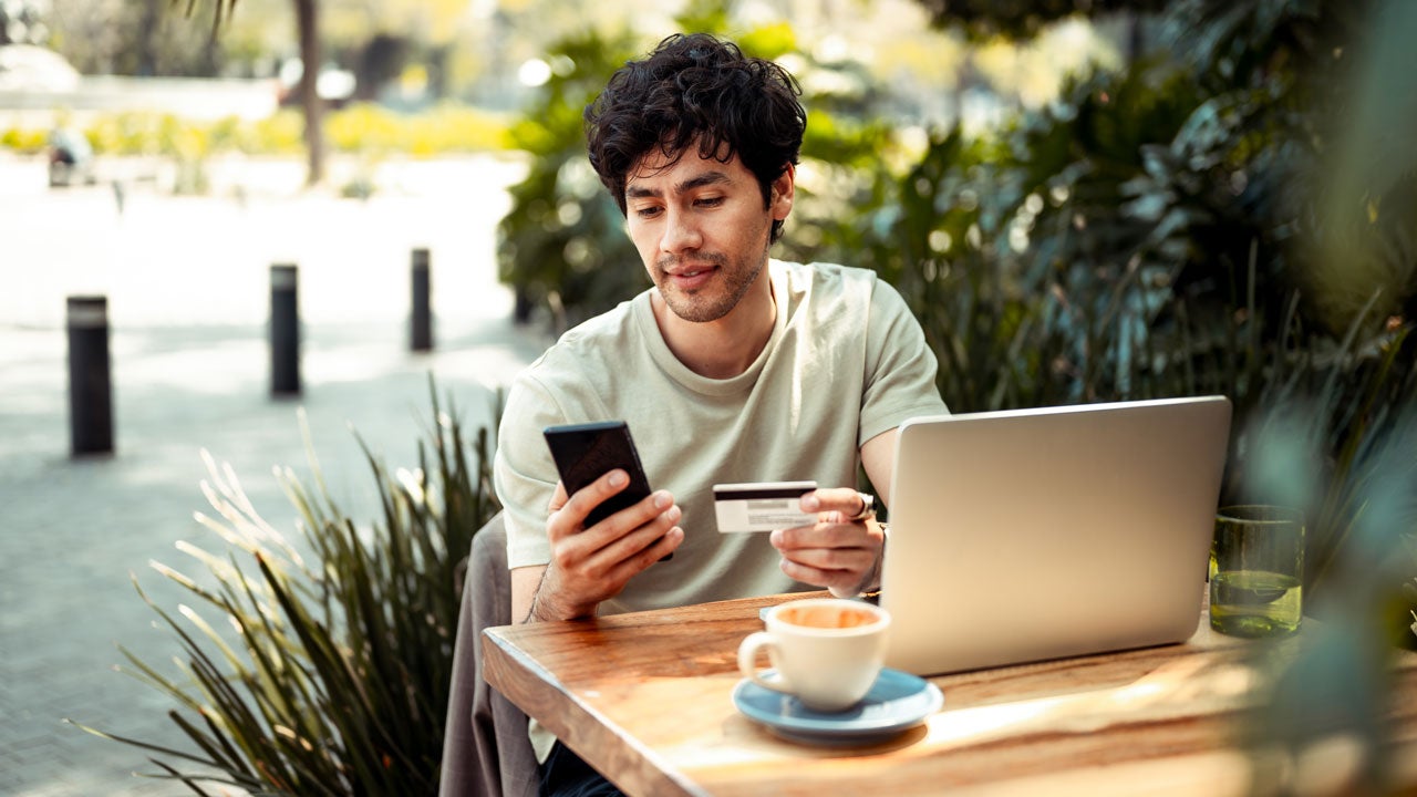 man looking at credit card sitting outdoors