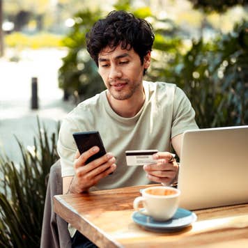 man looking at credit card sitting outdoors