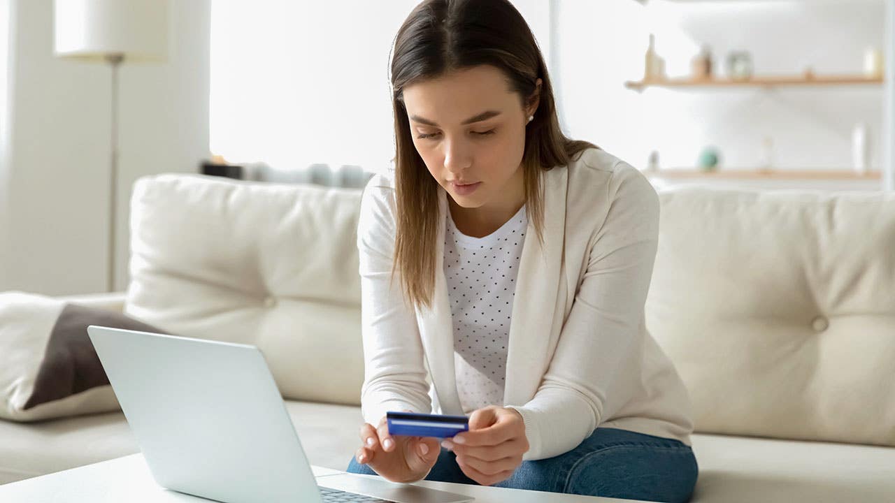 Focused young woman entering banking credit card information in computer application, making household payments online, booking flight tickets or hotel, purchasing goods or confirming transaction.
