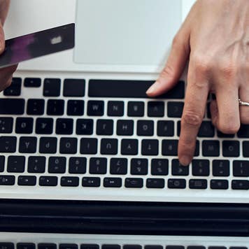 close up of woman's hand typing on a laptop and holding a credit card