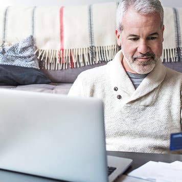 Senior man using a credit card at home