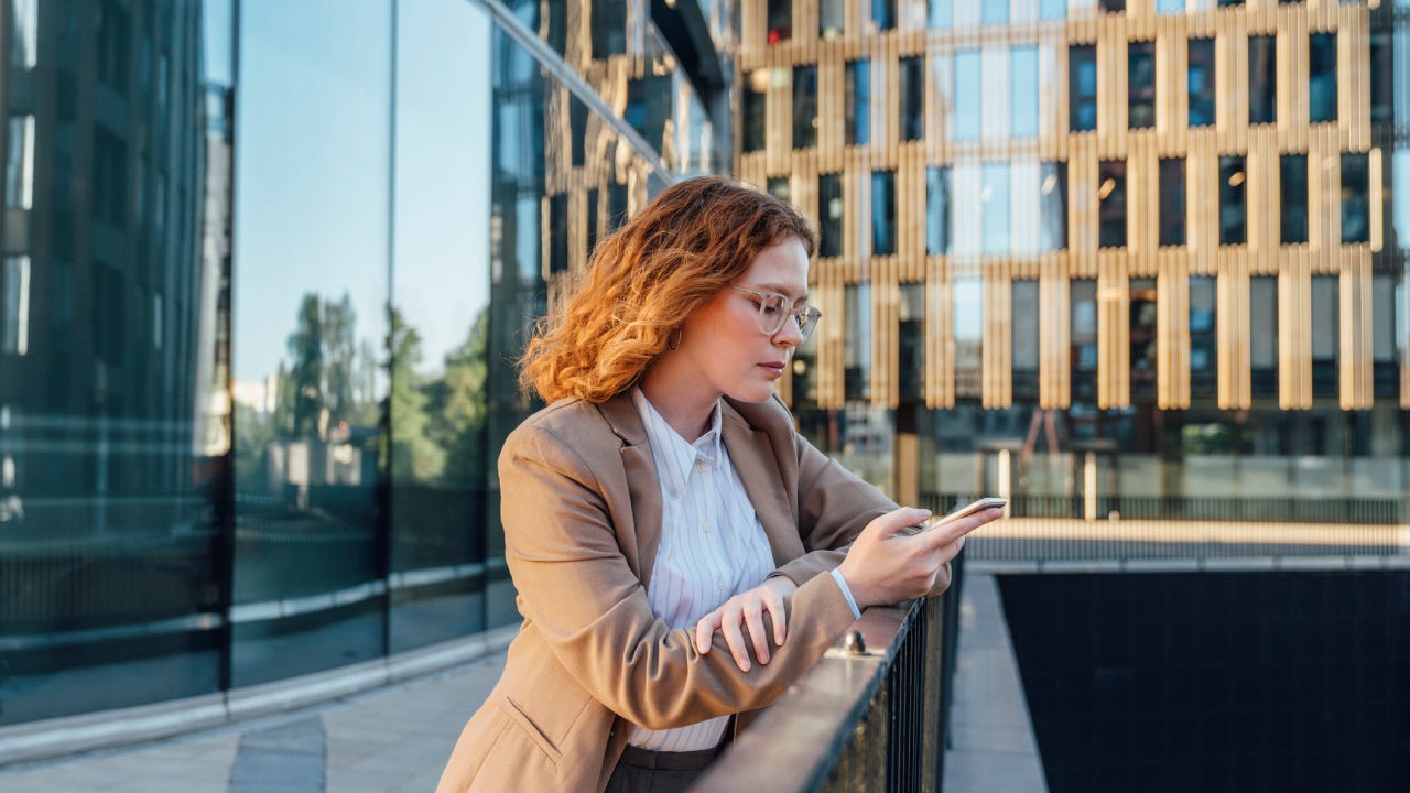 person using mobile phone leaning on railing