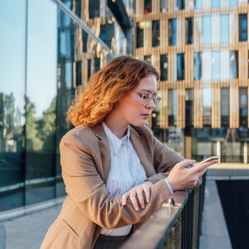 person using mobile phone leaning on railing