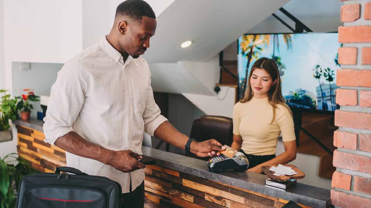 man using credit card at hotel reception desk