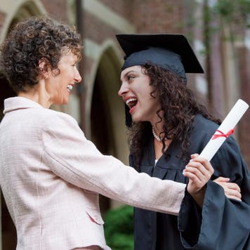 Mom and college graduate smile at graduation