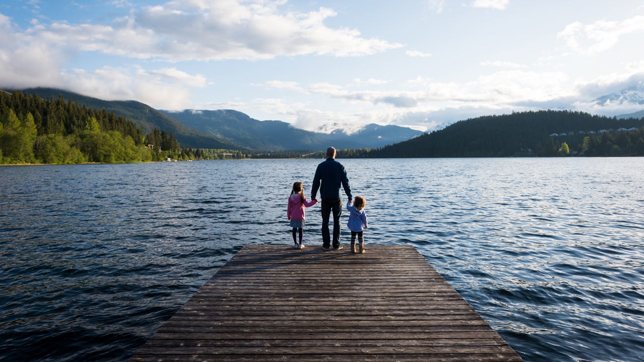 father and daughters standing on dock looking out over the lake