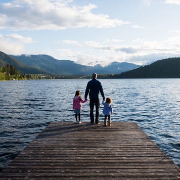 father and daughters standing on dock looking out over the lake