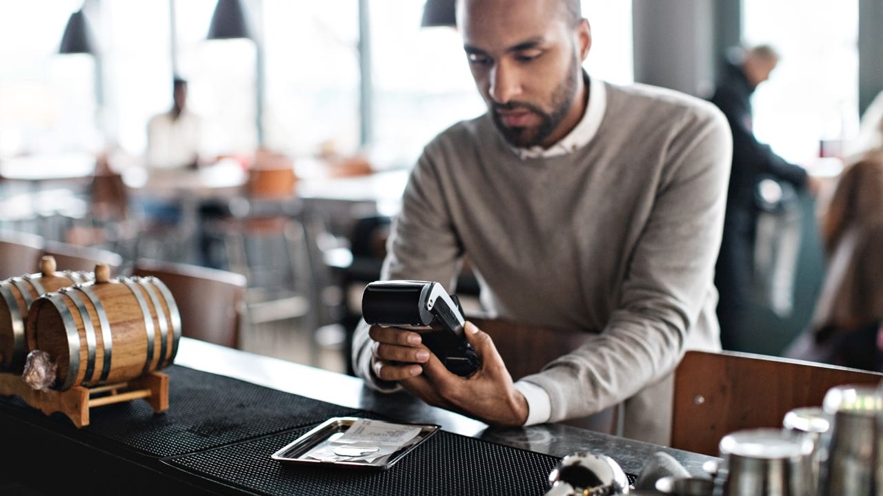 Customer using credit card reader at checkout counter in restaurant
