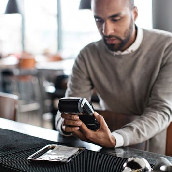 Customer using credit card reader at checkout counter in restaurant