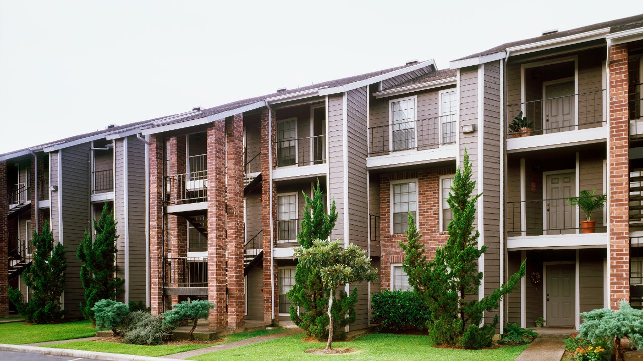 Front view of brick and siding condominium buildings from parking lot