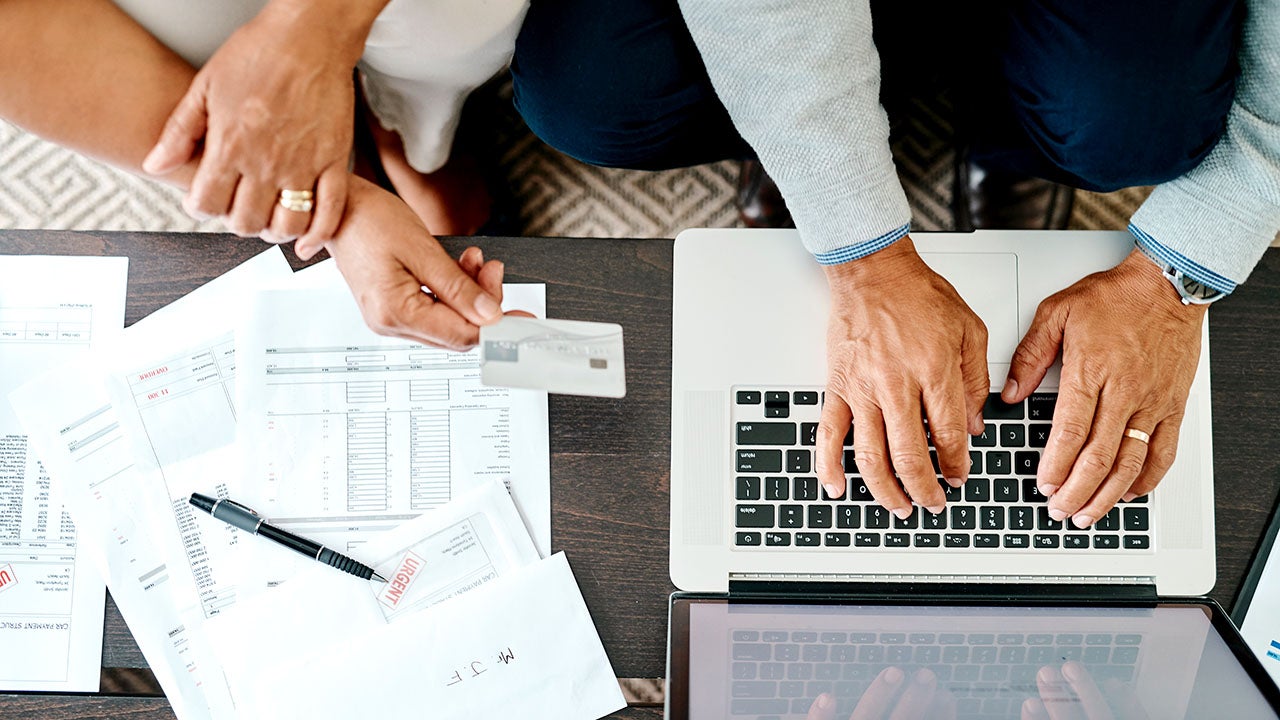 High angle shot of a couple using a laptop and credit card while sorting their finances together at home